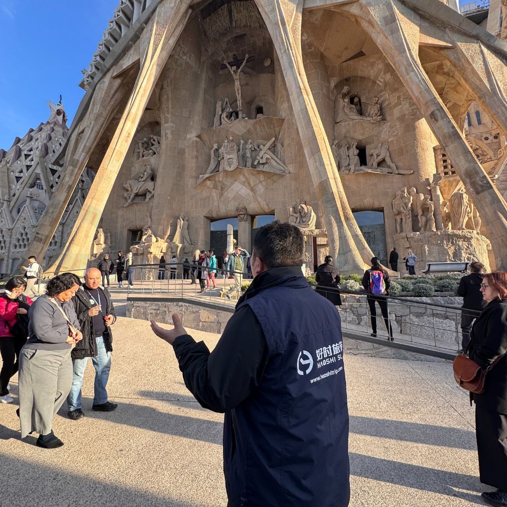 Chinese-speaking guide explaining the Sagrada Familia facade to visitors in Barcelona